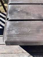 Close-up of Keter brand and squirrel-chewed corner on the plastic storage chest lid