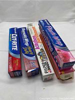 Four boxes of kitchen wraps including aluminum foil, wax paper, kitchen bags, and plastic wrap.