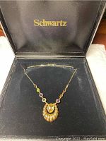 Necklace with pendant laid inside open black Schwartz box interior