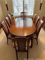 Overall view of dining table with leaves installed and eight chairs arranged.