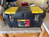 Closed Stanley toolbox with yellow latches sitting on a countertop