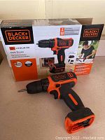 Black & Decker 12V cordless drill/driver with charger inside original box, orange and black handheld design