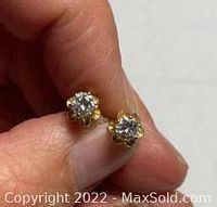 Front view of a single stud earring held between fingers showing diamond sparkle