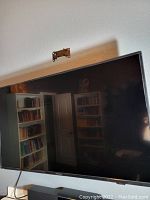 TV mounted on wall with shelf and bookcases in background