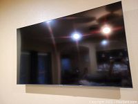 Front view of Sony 65" TV mounted on wall, showing screen and bezel.
