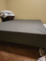 Full view of grey fabric box spring with base, showing solid and clean surface with slight wrinkles on cover.