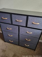 Front angle of the fabric dresser showing 9 drawers with wood handles and black frame.