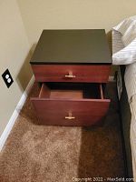 Front view of the nightstand with both drawers slightly open, showing interior space and drawer handles.