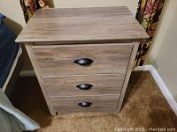 Front view of the nightstand showing three closed drawers and black metal handles.