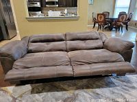 Front view of the brown reclining sofa with both footrests extended showing cushioned seats and backrests.
