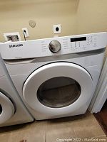 Front view of white Samsung dryer showing door, control knob and display panel