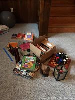 Photo showing assorted books, poker chips on a wooden board, wooden bookends, a decorative chicken figurine, and a small lantern on the floor.