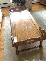 Full view of wooden coffee table showing raised tray top, scalloped edges, turned legs, and water marks on surface.