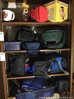 Multiple insulated cooler bags, drinkware, storage containers and a cardboard box on shelves
