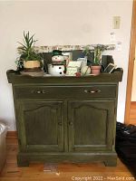 Full front view of the green painted dry sink showing two drawers and two cabinet doors, scratches visible on the paint finish.