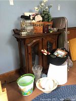 Wide view of wood cabinet with faux flowers, baskets, decorative plates, and miscellaneous items on and around it
