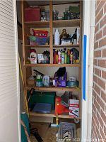 Shelf with assorted household and gardening products including pet bowls, cleaning sprays, containers, and a toy wheelbarrow