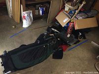 Photo of a black and green golf bag lying on the floor with some accessories visible around.