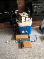 Shows Igloo cooler with two boxed Pampered Chef kitchen items on top, black folding chair, colorful umbrella, and a wrapped item on floor.