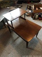 Full view of the two-tier wooden end table placed on carpet, showing overall design and top surfaces.