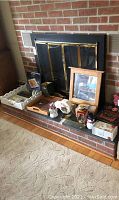Photo showing wooden trays, framed mirror with hooks, decorative bricks, lantern, tin on brick hearth under fireplace screen