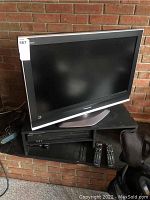 Panasonic LCD TV with silver stand and Sony DVD VHS player with two remotes underneath.