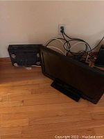 Panasonic 24-inch television Model TC-L24C3 with black frame, lying on the floor with cables visible behind it.