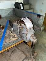 Full view of the heavy duty bench vice mounted on a metal workbench with visible rust and wear.