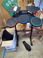 Full view of Guitar Hero drum kit standing on adjustable black plastic legs with foot pedal at base