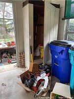 Overview of the storage area with various garden tools, extension cords, and miscellaneous items in boxes and bins.