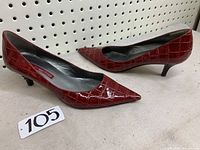Pair of burgundy/red Bandolier women's high heel shoes size 8.5 with crocodile embossed pattern shown side by side on shelf