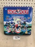 Full front view of Disney Monopoly board game metal tin box with colorful Disney theme park artwork and Monopoly logo.