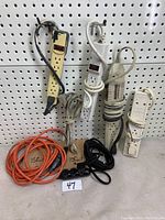 Overview of all extension cords and power bars against a pegboard background, showing different colors and lengths of extension cords and multiple power bars with switches.