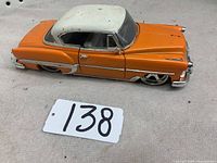 Side and angled views of the orange and white 1953 Chevrolet Bel Air model car showing paint finish, wheels, and chrome details