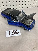 Front and top view of blue and black 1967 Shelby GT model with open driver door and hood showing engine detail.