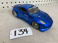 Blue metal Nissan Z model car facing forward with visible racing decals and silver wheels.