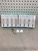 8 boxed LED E12/E14 filament candelabra bulbs on shelf with one unboxed bulb in front, clear glass candle style shape