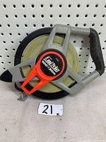 Full view of the Lufkin reel tape measure showing the handle, the tape wound within an open frame, and the measuring tape's metal hook.