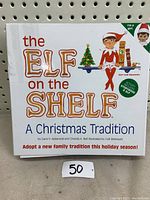 Closed storybook 'The Elf on the Shelf: A Christmas Tradition' with Christmas themed design and elf on cover.
