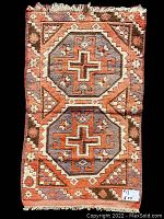 Full view of the geometric handmade antique Persian area rug showing front side with two octagonal medallions in orange and gray.