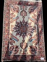 Full view of the handmade Turkish rug showing central medallion and border pattern, colors cream, red, and blue