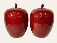 Front view of the pair of large oxblood glaze ginger jars showing smooth surface and finial tipped lids.