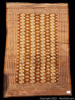 Full view of rust background Bokara rug with ivory elephant footprint motifs and ornate border