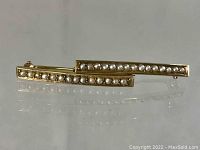 Pair of antique 14K gold seed pearl pins with one row of small pearls each, shown angled giving a clear view of the front and pearls.