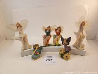 Front view of six used fairy figurines, showing variety of poses and colors including white, blue, purple, green, and multicolor skirts.