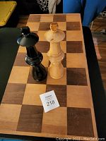 Top view of wooden chessboard with a natural and a black king piece