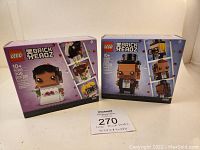 Front view of both Lego BrickHeadz boxes, Bride 40383 on left and Groom 40384 on right, showing product images and age 10+