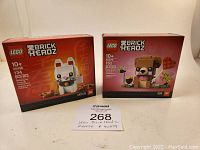 Front view of both LEGO BrickHeadz sets 40436 Lucky Cat and 40379 Valentine Bear, showing unopened boxes side by side against a white background.
