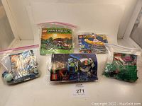 Five sealed plastic bags containing Lego pieces and instruction manuals for various Lego sets.