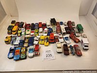 Photo showing 58 Matchbox cars arranged in rows, various styles and colors visible, showing some wear.